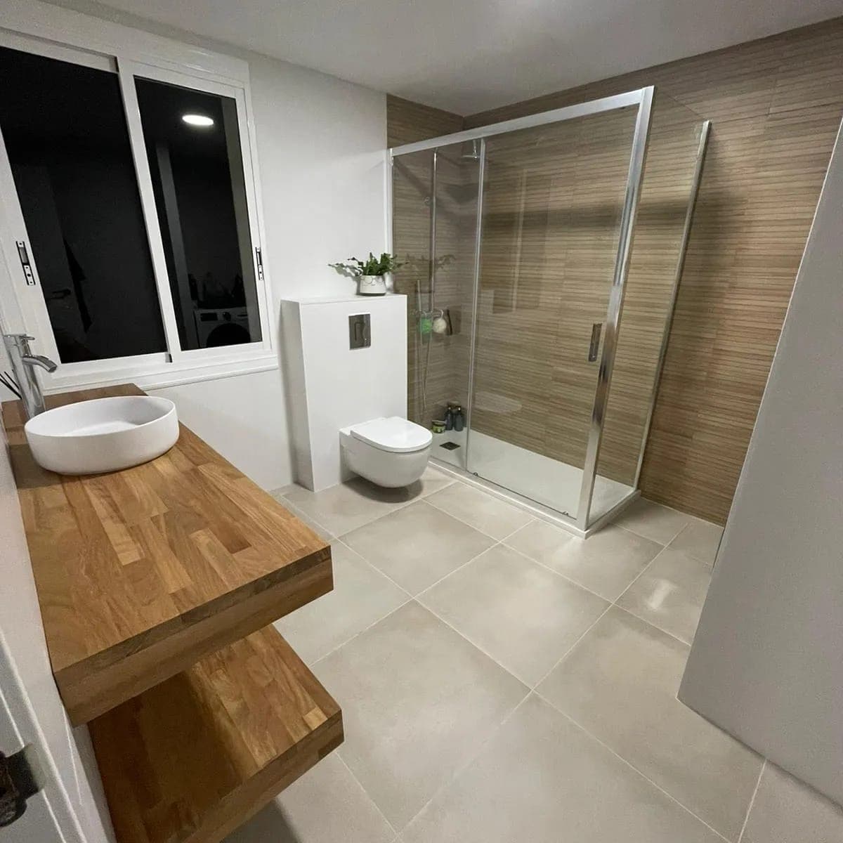 Baño con ducha de cristal y mueble de madera