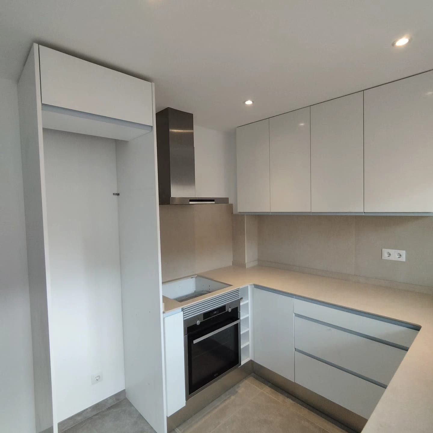 Cocina en U con armarios blancos y encimera de microcemento